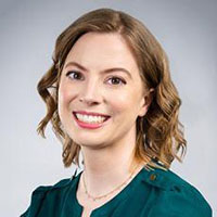 A headshot of a college professor in a green shirt